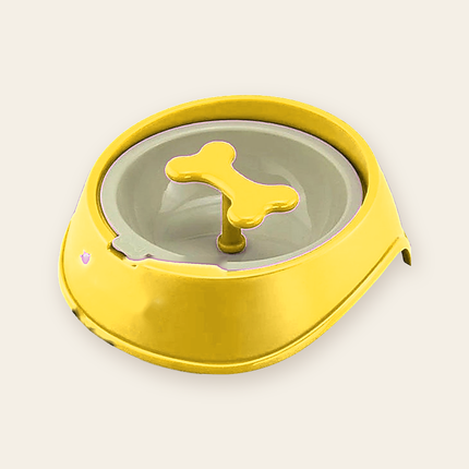 Gamelle anti-glouton jaune, vide, avec un fond gris clair et une pièce centrale en forme d’os